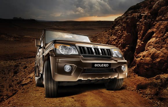 A brown Mahindra Bolero, a rugged Jeep-like SUV, on a rocky dirt road