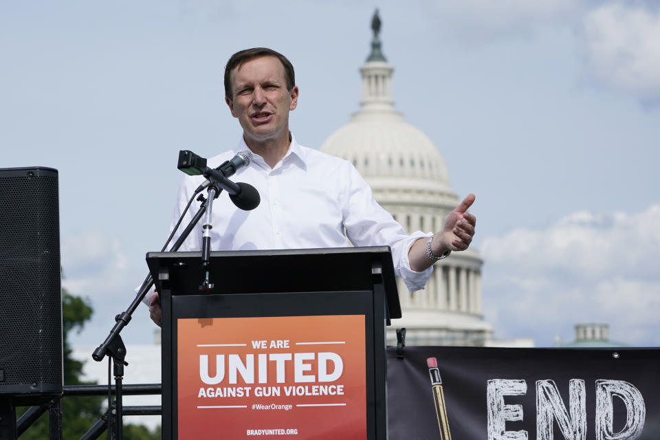 Sen. Chris Murphy stands behind a lectern with a sign reading: We Are United Against Gun Violence. The U.S. Capitol is in the background.