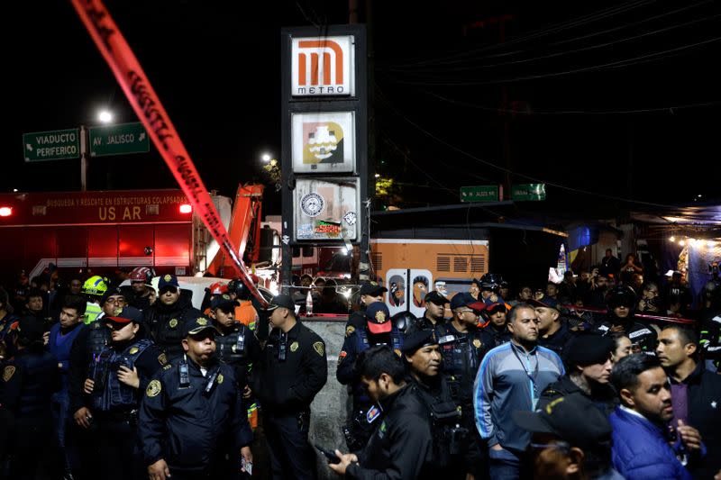 Police officers and onlookers stand outside the Tacubaya metro station after two trains collided, in Mexico City