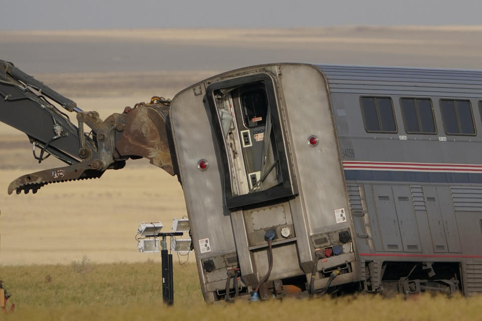 A piece of heavy equipment props up a leaning train car, Sunday, Sept. 26, 2021, that was part of an Amtrak train that derailed Saturday, near Joplin, Mont. The westbound Empire Builder was en route to Seattle from Chicago with two locomotives and 10 cars. (AP Photo/Ted S. Warren)