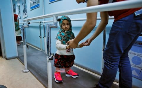 Maya Meri is guided by a prosthetic specialist as she tries out her new legs.   - Credit: Lefteris Pitarakis/AP