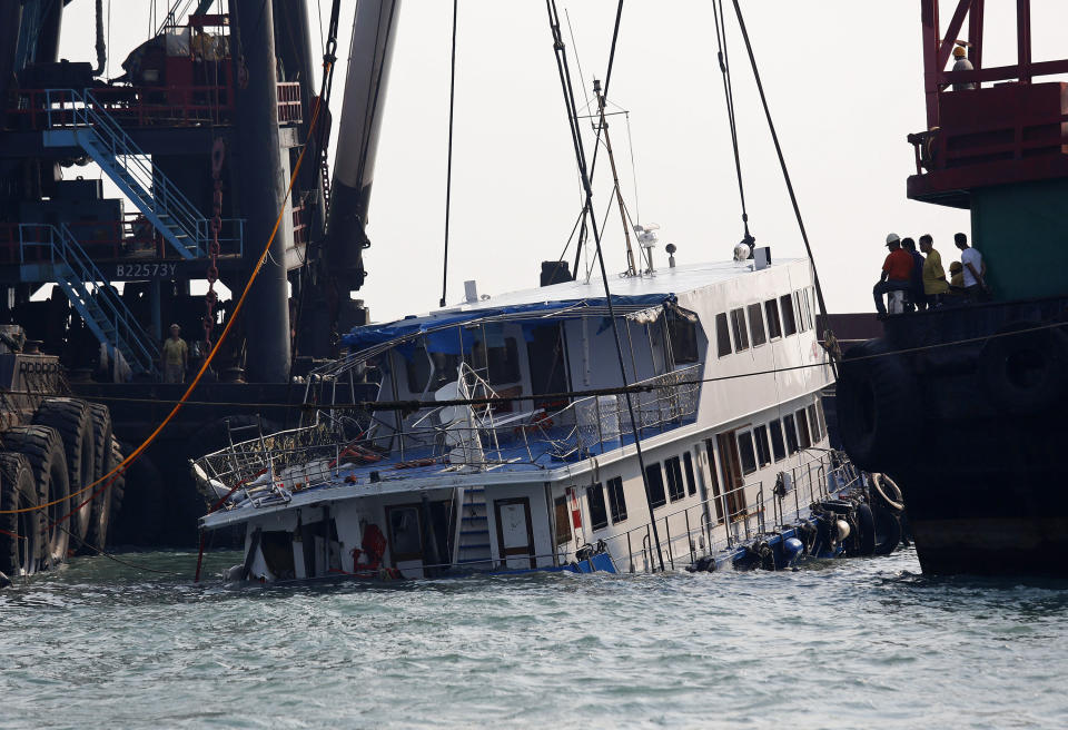 A half submerged boat is lifted by cranes Tuesday Oct. 2, 2012 after Monday night's collision near Lamma Island, off the southwestern coast of Hong Kong Island. The boat packed with revelers on a long holiday weekend collided with a ferry and sank, killing at least 36 people and injuring dozens, authorities said. (AP Photo/Vincent Yu)