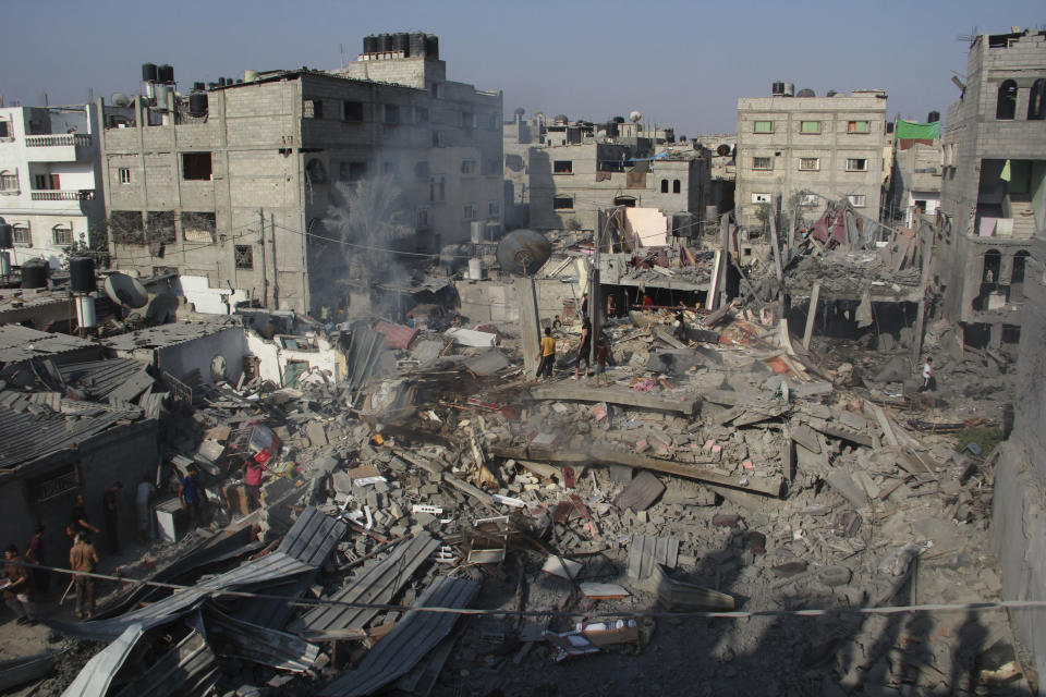 FILE - In this Saturday, Aug. 2, 2014 file photo, Palestinians stand on the rubble of houses destroyed in an Israeli strike in Rafah, southern Gaza Strip. The Israeli military said on Wednesday Aug. 15, 2018, its investigation focused on an Aug. 1, 2014, battle in the southern Gaza town of Rafah, one of the bloodiest incidents of the 2014 war, has found no criminal wrongdoing by Israeli forces, although human rights advocates accused the military of a whitewash.(AP Photo/Hatem Ali, FILE)