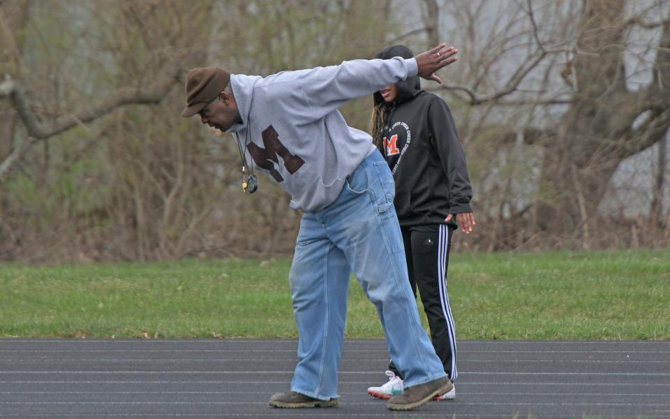 Tygers track coach Tyree Shine helps a runner with her form Thursday afternoon.