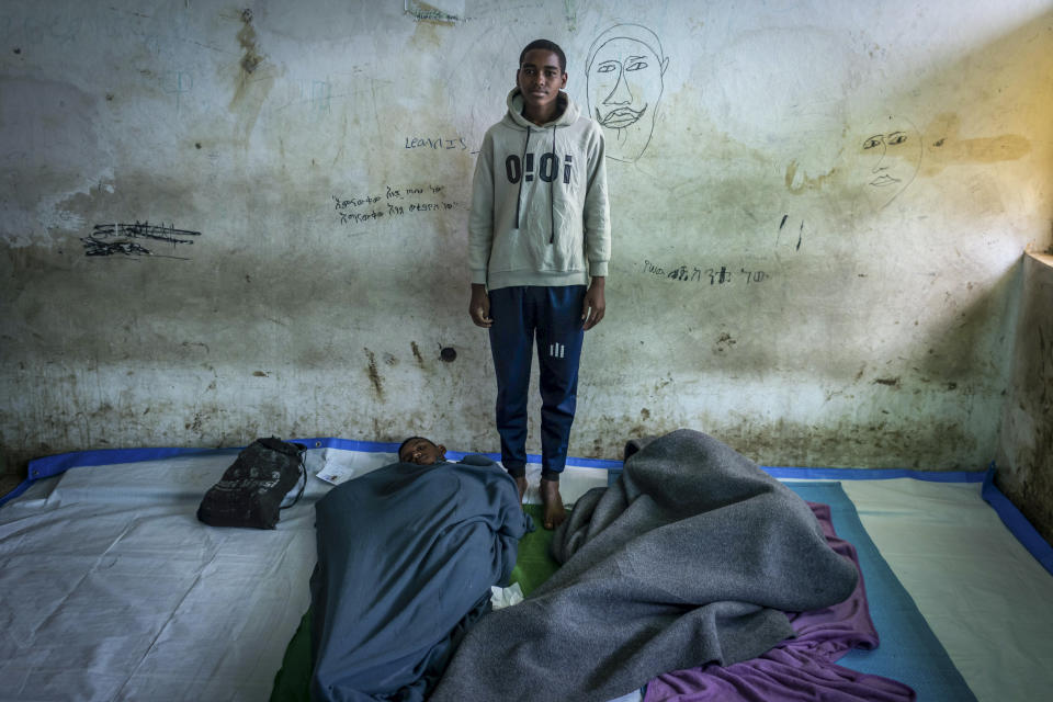 Mulu Adugna, 18 years old, poses for a photo in the room where he sleeps at a center for the internally-displaced in Debark, in the Amhara region of northern Ethiopia Friday, Aug. 27, 2021. Adugna says he fled his hometown of Addi Arkay with his brother and friends after he saw five members of his neighbor's family killed by artillery rounds from Tigrayan forces. (AP Photo/Mulugeta Ayene)