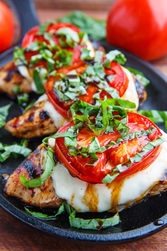 Three pieces of grilled chicken topped with mozzarella, tomato, basil, and balsamic drizzle