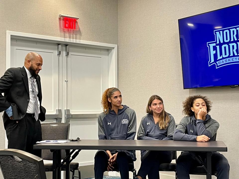 Darrick Gibbs (left) waits to speak at UNF's basketball media day in 2021. With him are turning players Jazz Bond, Rhetta Moore and Tiffany Tolbert.