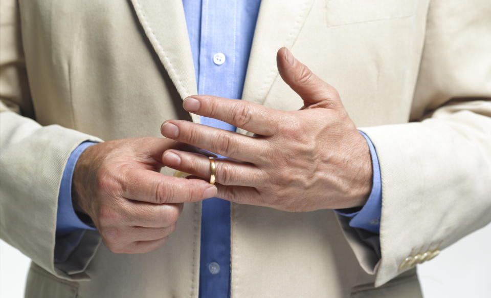 Person removing wedding ring from finger, suggesting themes of separation or divorce