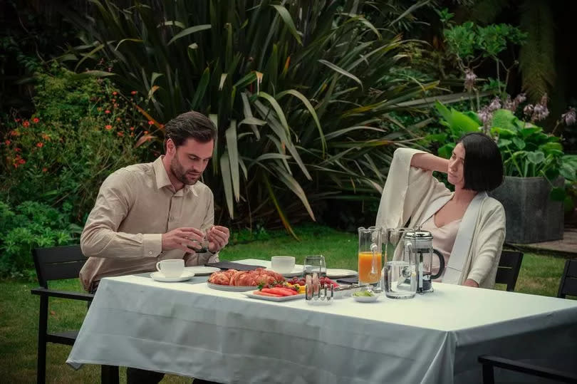 A man and woman sat on a dinner table outdoors