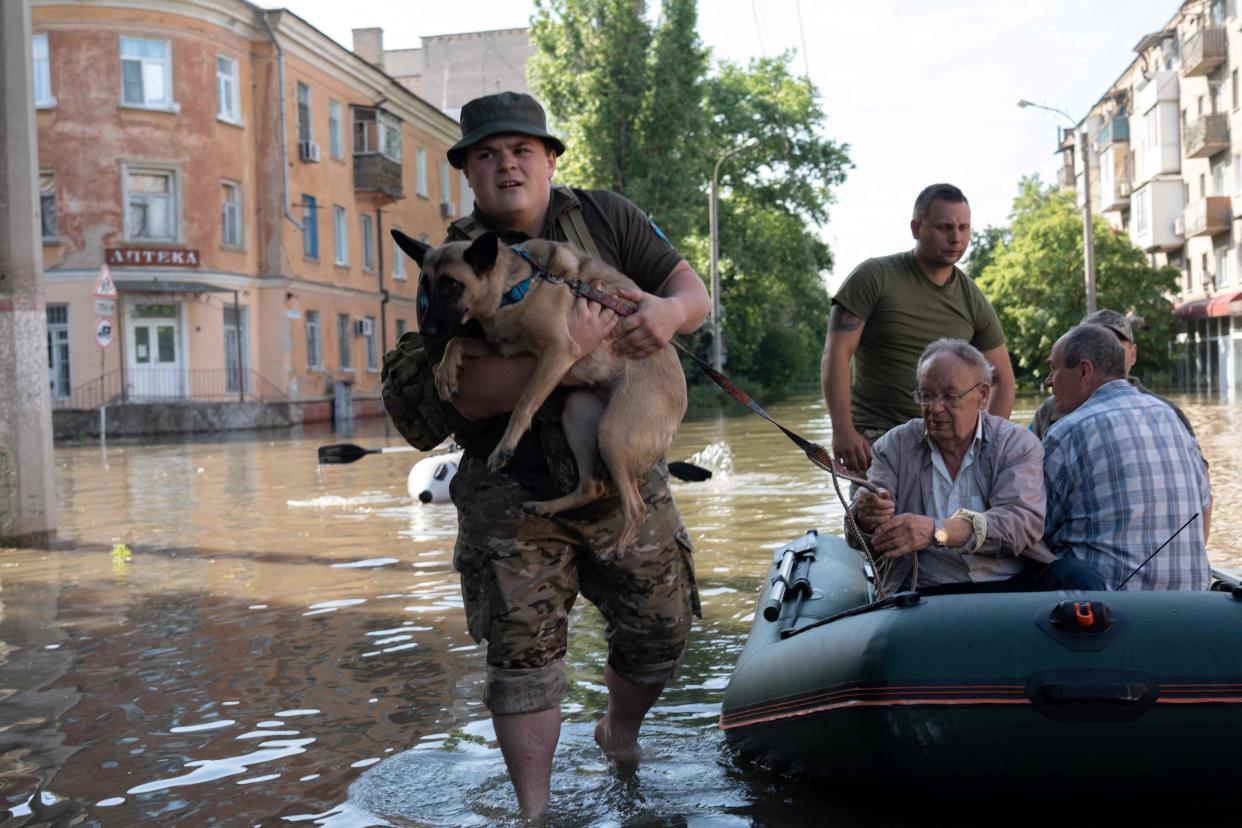 Ukrainian servicemen help local residents during an evacuation from a flooded area in Kherson (AFP via Getty Images)