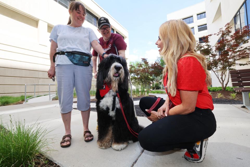 Stephanie Jacobs of Intermountain Therapy Animals sits next to her dog Biscuit as Lisa Dobkins and Brian Dobkins pet him at St. Marks Hospital in Salt Lake City on Monday, June 12, 2023. The canine therapy program is resuming following COVID-19. | Scott G Winterton, Deseret News