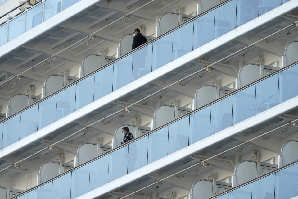 Passengers stand on the balcony of the cruise ship Diamond Princess anchored off the Yokohama Port in Yokohama, near Tokyo Monday, Feb. 10, 2020. China reported a rise in new virus cases on Monday, possibly denting optimism disease control measures that have isolated major cities might be working, while Japan reported dozens of new cases aboard the quarantined cruise ship. (AP Photo/Eugene Hoshiko)