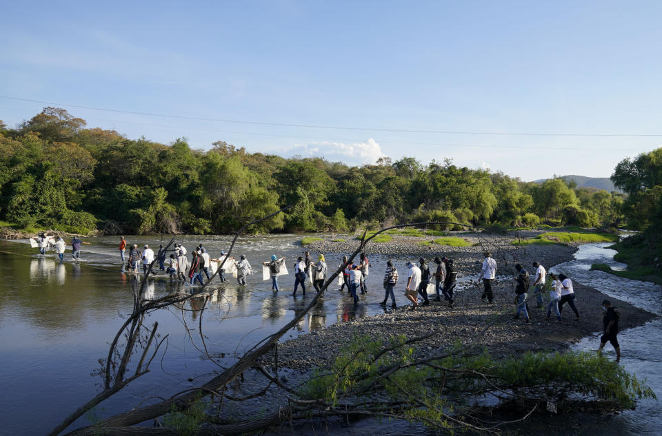 Residents from Aguililla and other nearby communities wade across a river to confront an army squad blocking a dirt road leading out of Jalisco territory, in Loma Blanca, Mexico, Tuesday, Nov. 16, 2021. The residents, who are fed up with the army’s strategy of simply separating the Jalisco and the Michoacan-based Viagras gangs, want the army to either fight both cartels, or at least let the two gangs fight it out amongst themselves. (AP Photo/Eduardo Verdugo)