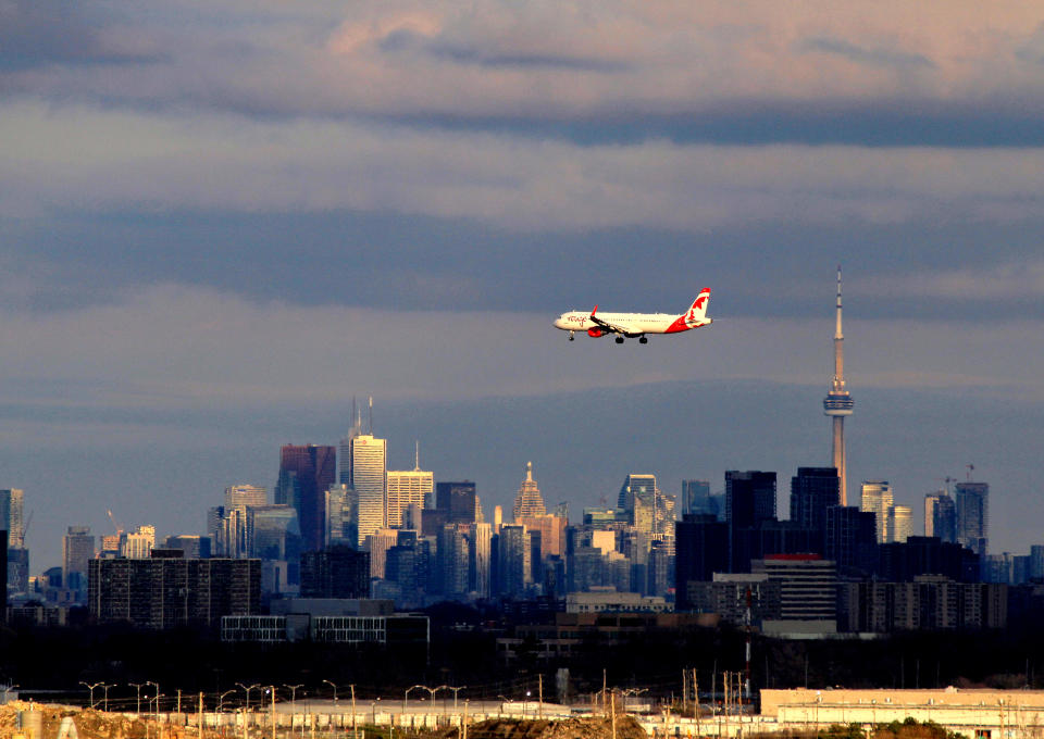 A plane is arriving at Toronto Pearson International Airport while the sun is setting on downtown Toronto. This view is captured from the Final Approach Danville Terminal, an aviation-themed park space situated on a man-made 25-metre-tall platform designed for watching planes as they arrive and depart, in Mississauga, Ontario, on March 15, 2024. (Photo by Mike Campbell/NurPhoto via Getty Images)