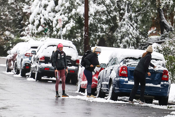 People brush off their car windows during an early season snow storm in Boulder, Colorado.