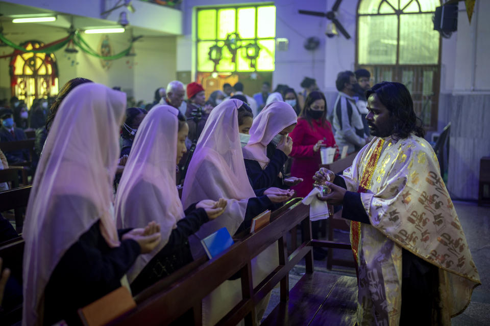 Indian Christians receive the holy communion from a priest after attending a Christmas mass at Saint Mary's church in Noida, a suburb of New Delhi, India, Saturday, Dec. 25, 2021. (AP Photo/Altaf Qadri)