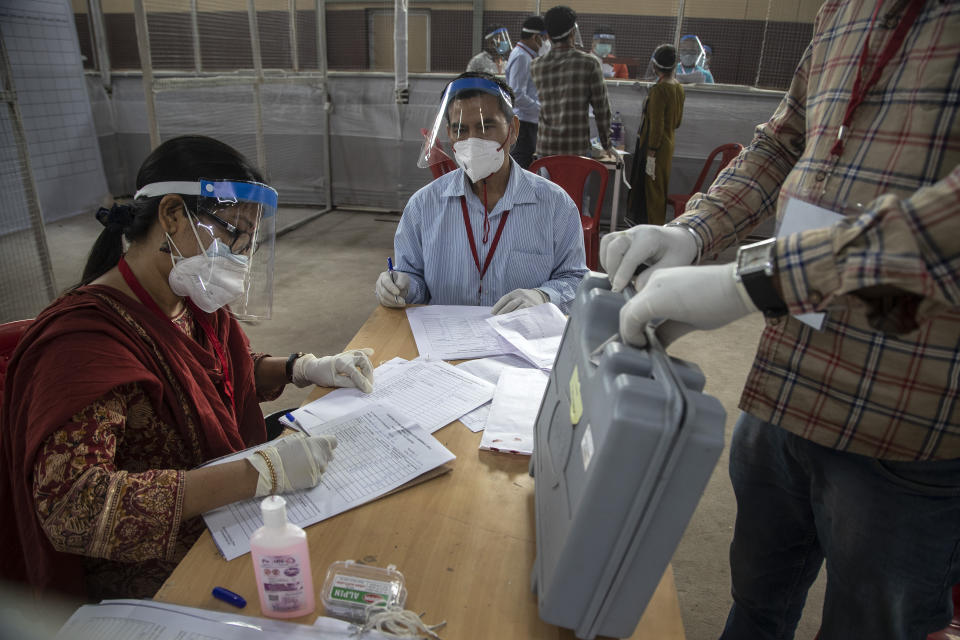 Election officials sit wearing masks and face shields during the counting of votes of Assam state assembly election in Gauhati, India, Sunday, May 2, 2021. With Indian hospitals struggling to secure a steady supply of oxygen, and more COVID-19 patients dying amid the shortages, a court in New Delhi said it would start punishing government officials for failing to deliver the life-saving items. (AP Photo/Anupam Nath)