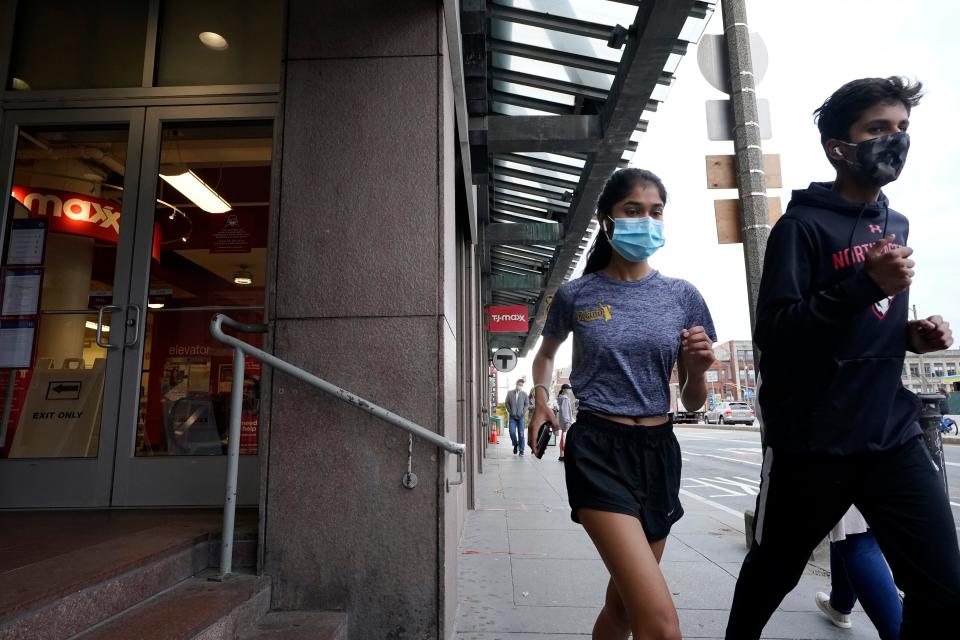 Runners wear masks while jogging along a sidewalk Oct. 27, 2020, in Boston.