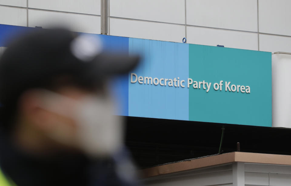 A police officer stands near the sign of the Democratic party of Korea in Seoul, South Korea, Tuesday, March 19, 2019. International journalists' organizations have expressed concern over South Korea's press freedoms after the country's ruling party singled out a Bloomberg reporter over what it claimed was a "borderline treacherous" article insulting President Moon Jae-in, resulting in threats to the reporter's safety. (AP Photo/Lee Jin-man)