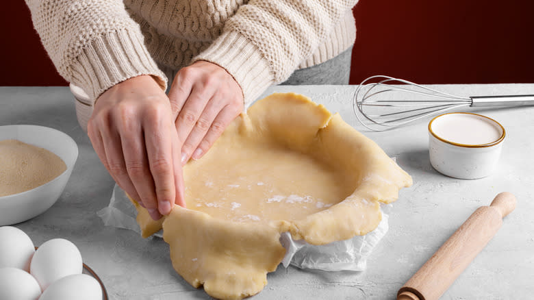 Hands shaping pie crust tin