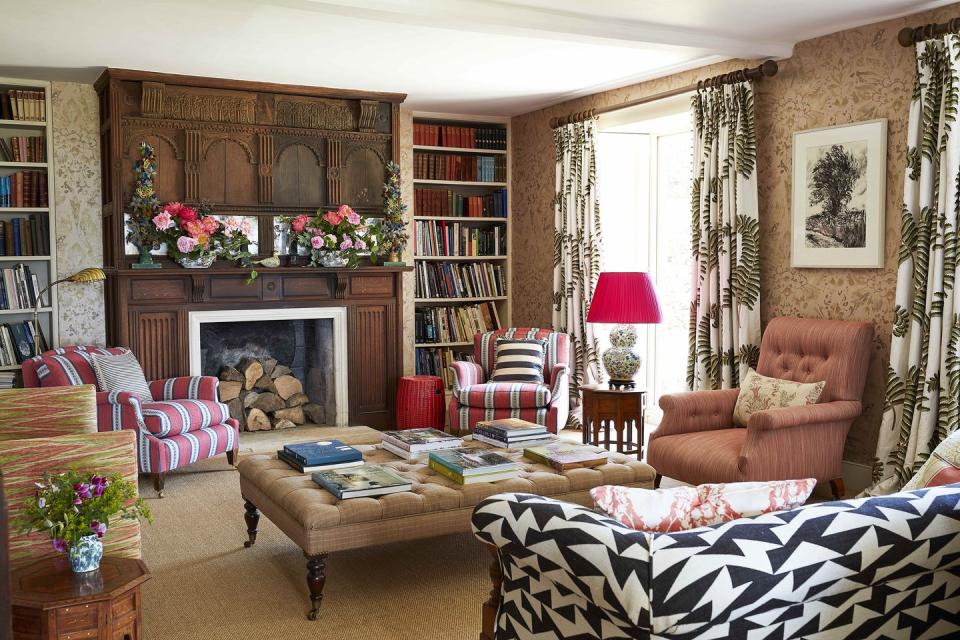 a parlor full of pattern has a sofa and several chairs and bookshelves and an upholstered ottoman