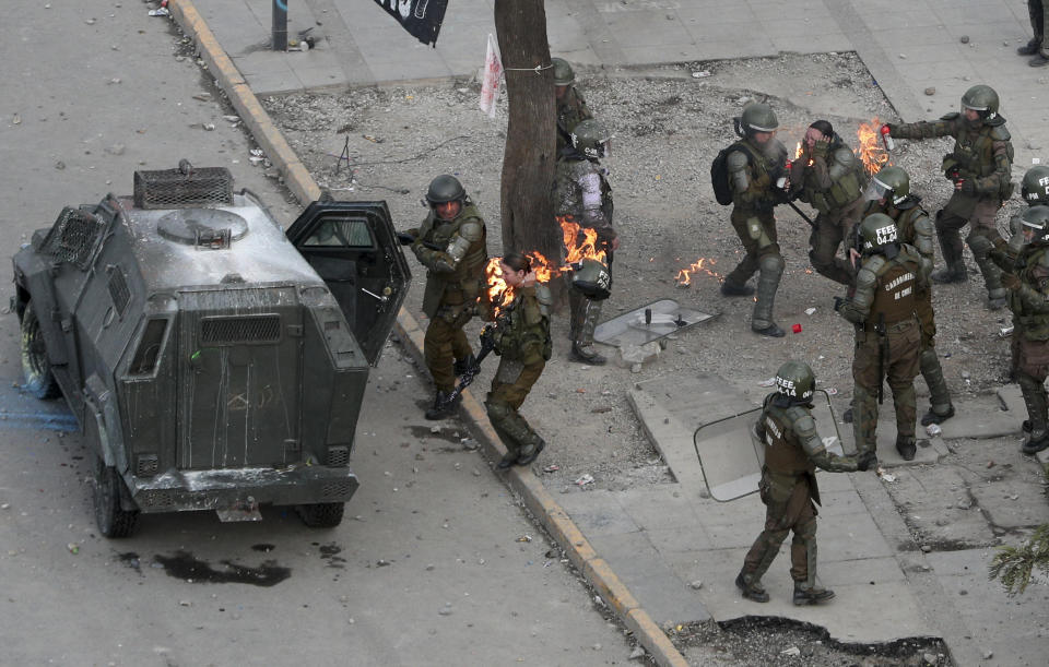 Police run after being hit with a gasoline bomb thrown by protesters during an anti-government protest in Santiago, Chile, Monday, Nov. 4, 2019. Chile has been facing weeks of unrest, triggered by a relatively minor increase in subway fares. The protests have shaken a nation noted for economic stability over the past decades, which has seen steadily declining poverty despite persistent high rates of inequality. (AP Photo/Esteban Felix)