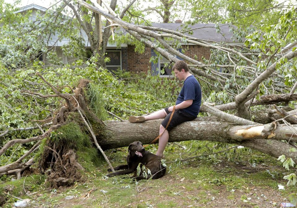 Caleb Emerson and his dog "Luke" rest in front of his Seventh Ave. home in Athens, Ala., Tuesday, April 29, 2014. A tornado took down the tree he is seated on. (AP Photo/The Decatur Daily, John Godbey)