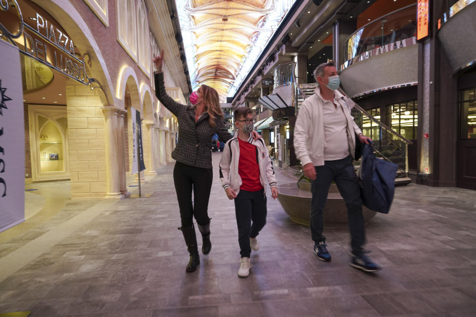 Passengers, Ilaria Gelli, 48, left, Federico Marzocchi, 45, right, and and their son Matteo Marzocchi, 10, walk on board the MSC Grandiosa cruise ship in Civitavecchia, near Rome, Wednesday, March 31, 2021. MSC Grandiosa, the world's only cruise ship to be operating at the moment, left from Genoa on March 30 and stopped in Civitavecchia near Rome to pick up more passengers and then sail toward Naples, Cagliari, and Malta to be back in Genoa on April 6. For most of the winter, the MSC Grandiosa has been a lonely flag-bearer of the global cruise industry stalled by the pandemic, plying the Mediterranean Sea with seven-night cruises along Italy’s western coast, its major islands and a stop in Malta. (AP Photo/Andrew Medichini)