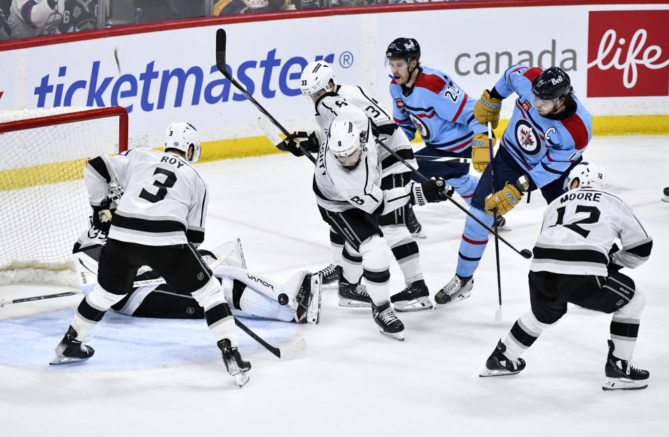 Los Angeles Kings goaltender Cam Talbot, bottom left, makes a save on Winnipeg Jets' Adam Lowry (17) as Matt Roy (3) and Drew Doughty (8) defend during the third period of an NHL hockey game in Winnipeg, Manitoba, on Monday, April 1, 2024. (Fred Greenslade/The Canadian Press via AP)