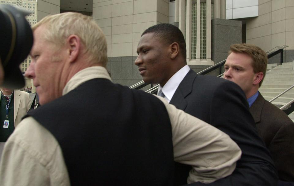 FILE - In this Feb. 22, 2000, file photo, Kansas City Chiefs wide receiver Tamarick Vanover, center, is guided towards a waiting car outside the Federal Courthouse in Kansas City, Mo. Former NFL players Clinton Portis, Tamarick Vanover and Robert McCune pleaded guilty for their roles in a nationwide healthcare fraud scheme, the U.S. Department of Justice announced Tuesday, Sept. 7, 2021. (AP Photo/Cliff Schiappa, File)