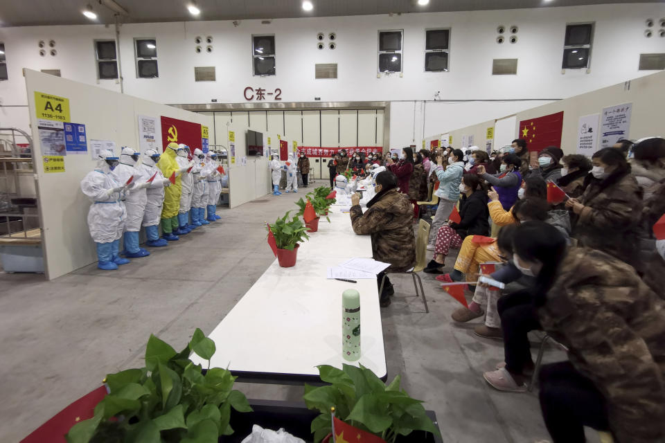 In this Feb. 28, 2020, photo released by Zhang Junjian, medical workers wearing protective suits in the Wuhan Living Room Temporary Hospital read poetry for patients in Wuhan in central China's Hubei province. The hospital is the largest of 16 temporary hospitals set up in gyms and other locations to handle an overflow of patients and try to stem the spread of the coronavirus by separating them from the rest of the city's 11-million inhabitants. (Zhang Junjian via AP)