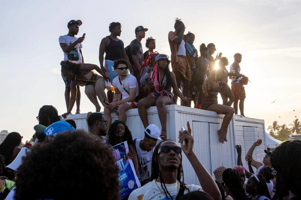 People stand on a shack used for storing beach equipment on South Beach during Spring Break in Miami Beach, Florida, on Saturday, March 18, 2023.