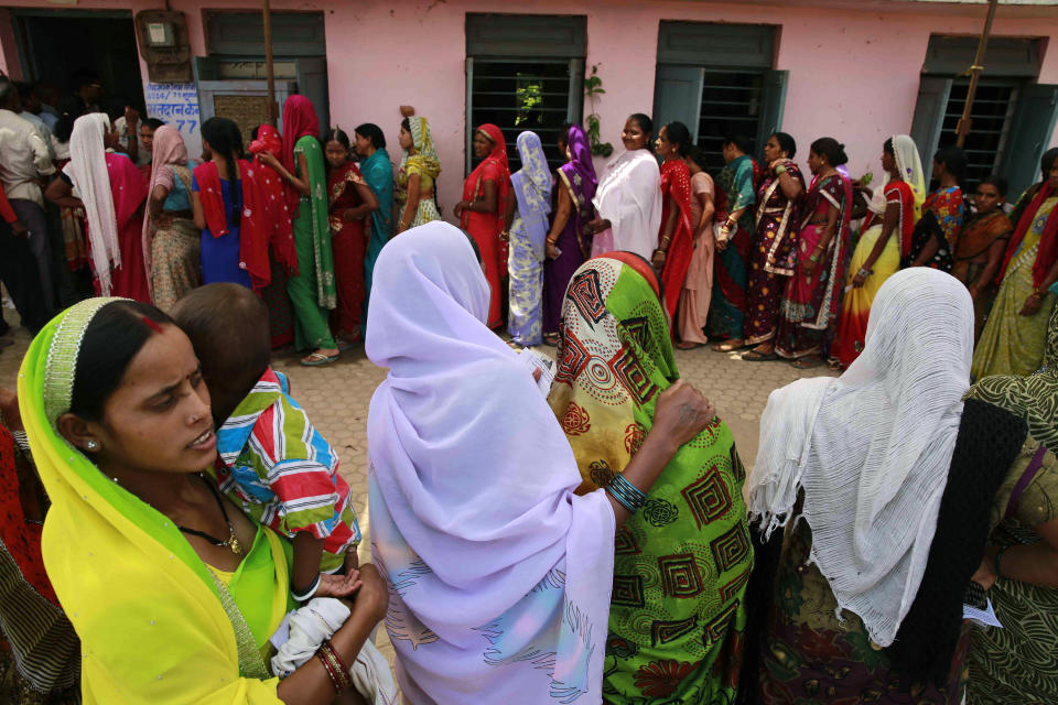 Indian women stand in a queue to cast their votes, outside a polling station in Rajnandgaon, in the central Indian state of Chhattisgarh, now the center of India's four-decade Maoist insurgency, Thursday, April 17, 2014. Indians cast ballots Thursday on the biggest day of voting in the country's weekslong general election, streaming into polling stations even in areas where rebels threatened violence over the plight of India's marginalized and poor. (AP Photo/Rafiq Maqbool)