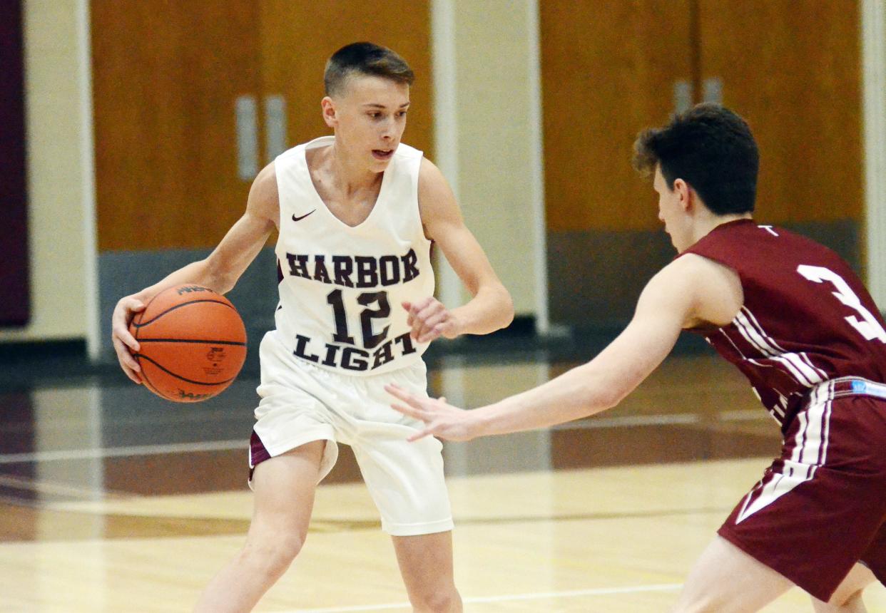 Harbor Light guard Landon Jakeway (left) drives on Traverse City Christian guard Jonah Mleko during the first half of the season opener Monday.