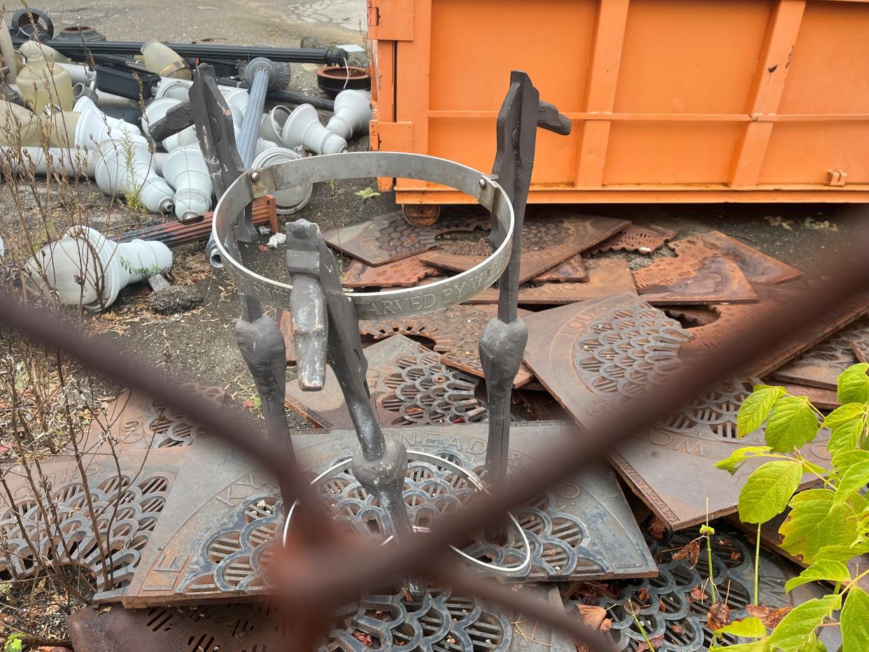 A mangled tree guard designed by a Kentucky artist sits next to a dumpster and old street lights in a city of Louisville scrapyard.