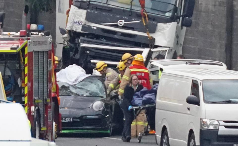 Pictured is a Porsche under the truck as emergency services work at the scene in Kew in Melbourne.