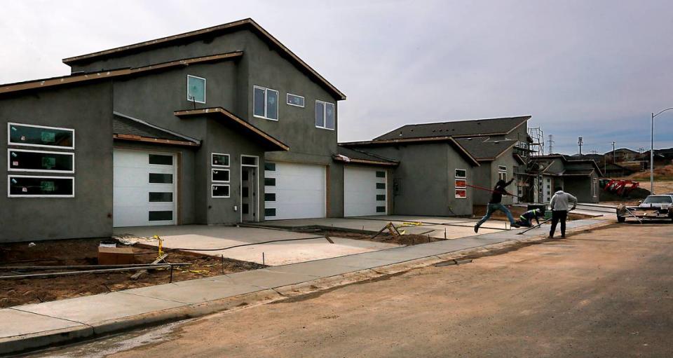Concrete workers smooth out freshly poured sidewalks in front of a group of tri-plex homes on South Nelson Street at West 33rd Avenue in Kennewick.