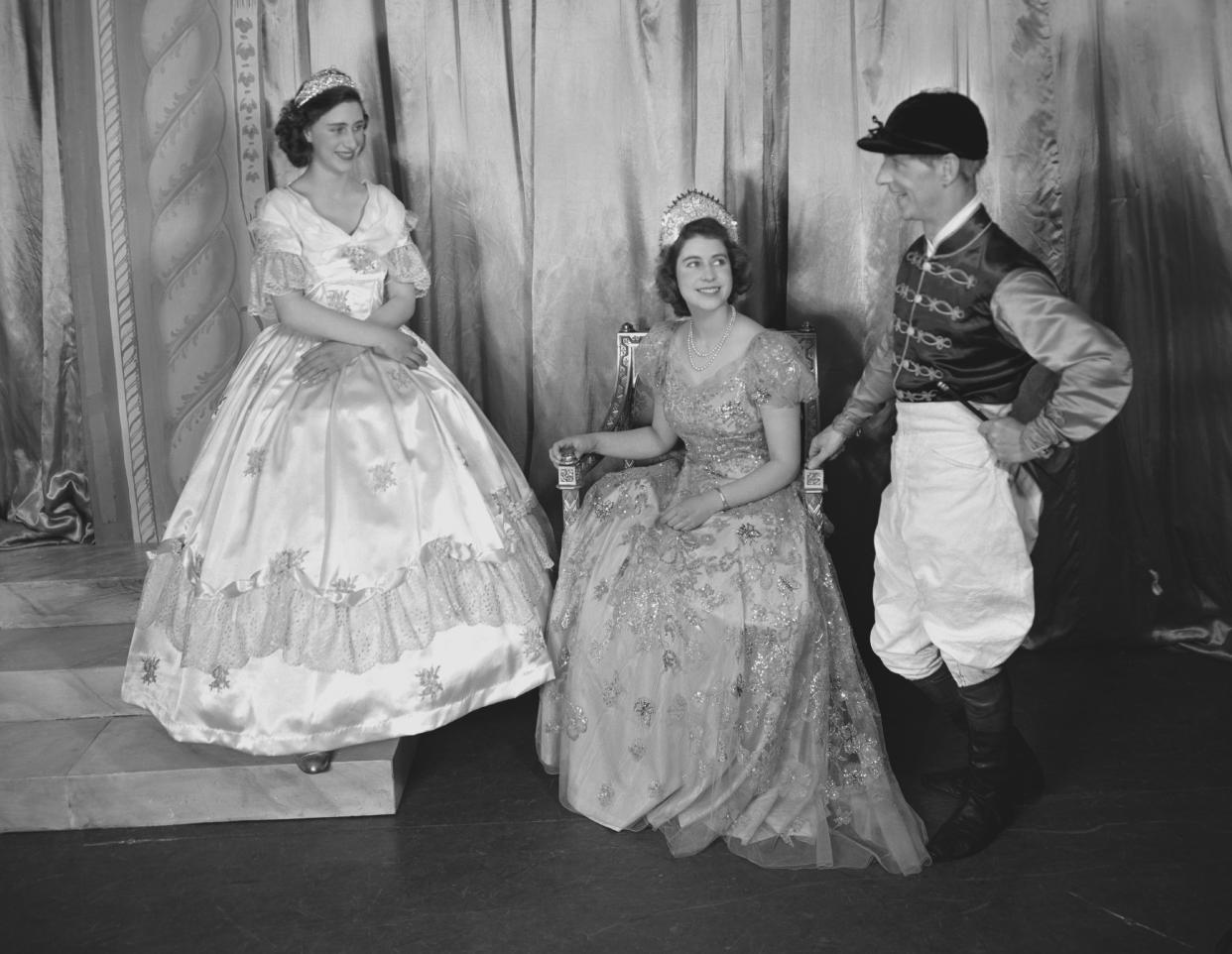 Princess Margaret (1930-2002) and Princess Elizabeth (Queen Elizabeth II), both dressed in elaborate gowns, pictured alongside a fellow performer during a royal pantomime production of 'Old Mother Red Riding Boots' at Windsor Castle, Berkshire, Great Britain, 22 December 1944. (Photo by Lisa Sheridan/Studio Lisa/Getty Images)