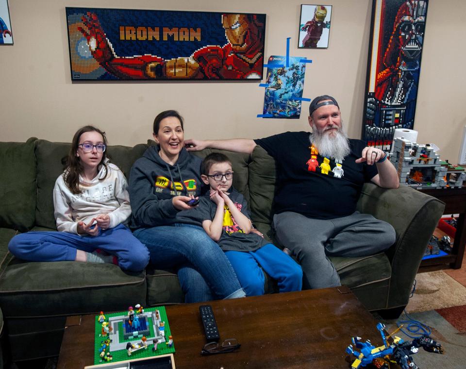 Liz Puleo, second from left, a contestant on the Fox television show "Lego Masters," views a recording of a show in the family basement, Oct. 3, 2022. With her are other members of her family, from left, daughter Julianna, 11; son Benjamin, 9; and husband Marc.