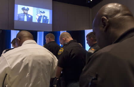 Policemen bow their heads in prayer under images of officers Liquori Tate and Benjamin Deen during a vigil service for the two officers who were killed during a traffic stop, in Hattiesburg, Mississippi May 11, 2015. REUTERS/Lee Celano