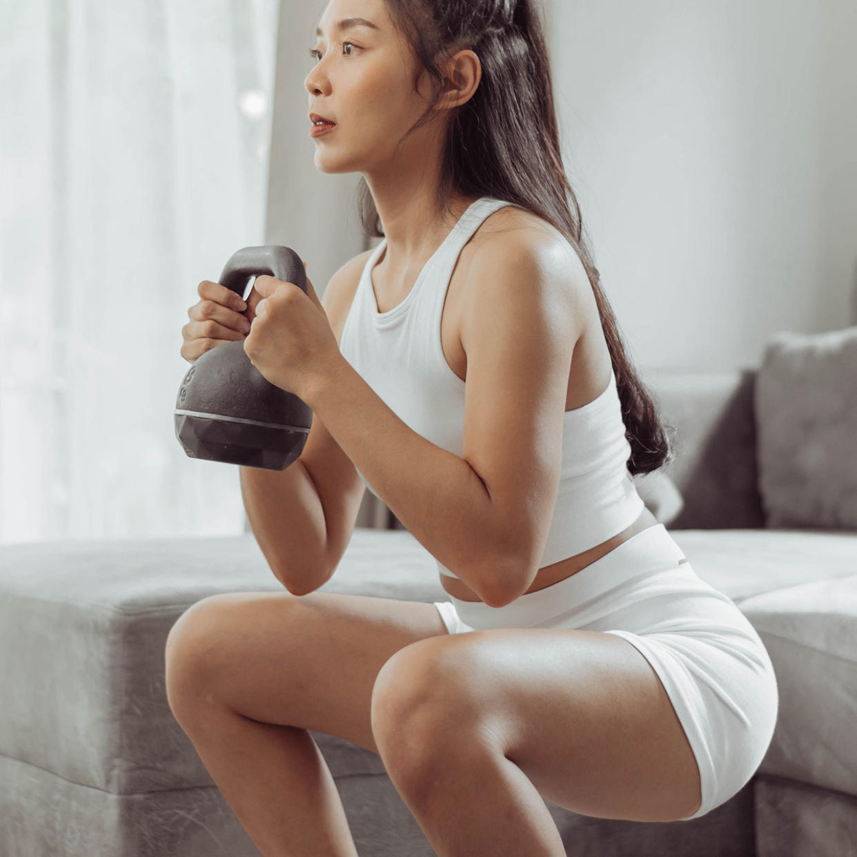 woman exercising at home with kettlebell squat