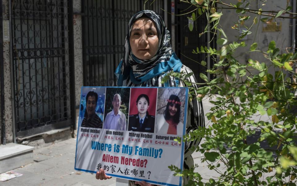 Uighur exile Milikeziti Hebibul, 35, holds photographs of her family members, who she believe are detained in China, in Zeytunburnu, a suburb of Istanbul - Sam Tarling for The Telegraph 