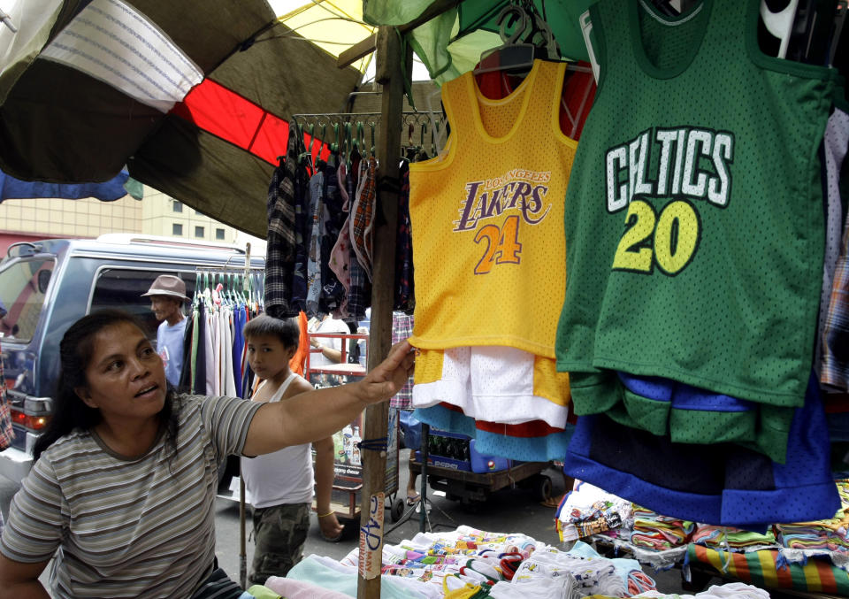 FILE - A street vendors shows basketball jerseys Saturday, June 5, 2010, in Manila's Divisoria shopping district, Philippines. Considering 110 million people live in the Philippines, it’s not feasible that they all would be basketball fans. “But it’s close,” said Tim Cone, the country’s winningest coach. (AP Photo/Pat Roque, File)