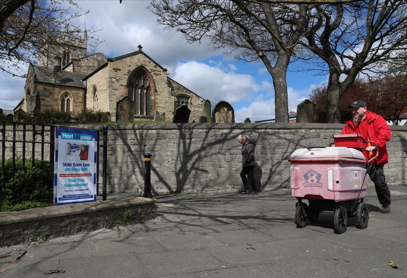 People walk past an election poster ahead of tomorrow's local elections, in Hartlepool