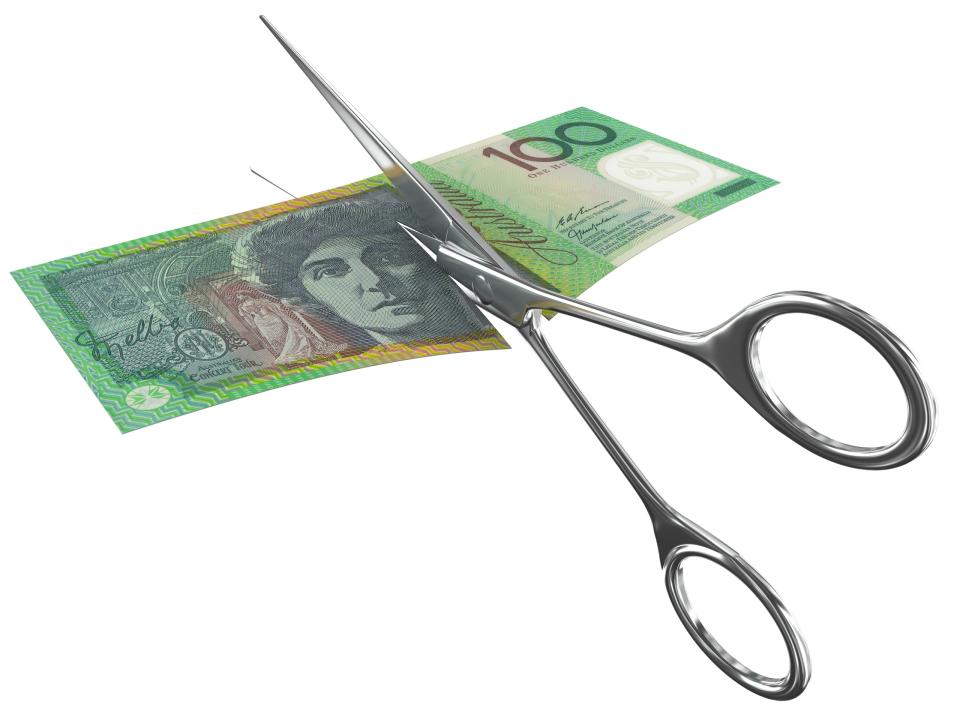 Australian $100 bank note being cut in half with scissors.