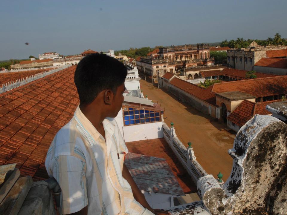 A boy looks out at a row of Chettinad mansions in India.