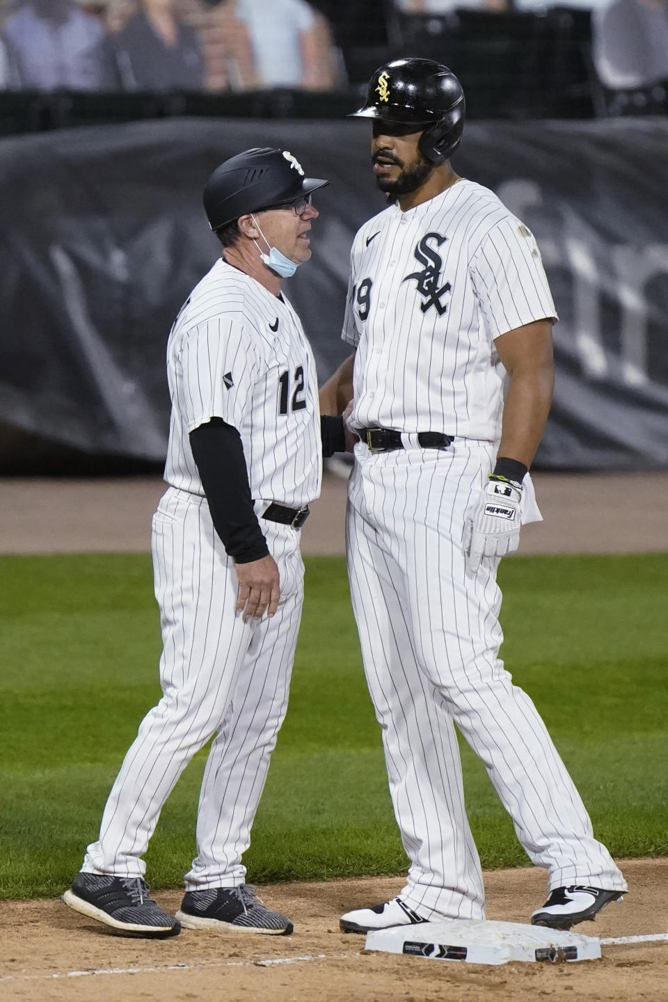 Chicago White Sox's Jose Abreu, right, is congratulated by third base coach Nick Capra after his three-run double during the fourth inning of a baseball game against the Chicago Cubs in Chicago, Saturday, Sept. 26, 2020. Abreu had advanced to third on an error on the play. (AP Photo/Nam Y. Huh)