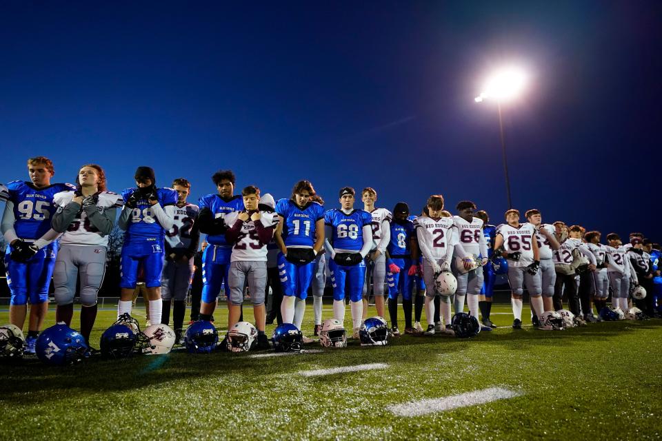 Lewiston High School and Edward Little High School players stand together, Wednesday, Nov. 1, 2023, prior to their high school football game in Lewiston, Maine. Locals seek a return to normalcy after a mass shooting on Oct. 25. (AP Photo/Matt York)