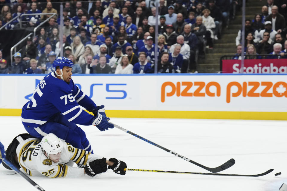 Toronto Maple Leafs' Ryan Reaves is checked by Boston Bruins' Brandon Carlo (25) during the second period of action in Game 3 of an NHL hockey Stanley Cup first-round playoff series in Toronto on Wednesday, April 24, 2024. (Nathan Denette/The Canadian Press via AP)