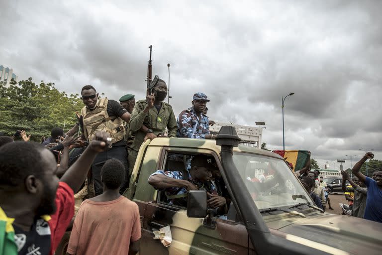 La gente celebra mientras las fuerzas de seguridad conducen por las calles de Bamako, Malí, el 19 de agosto de 2020, un día después de que el Ejército depusiera al presidente Ibrahim Boubacar Keita 